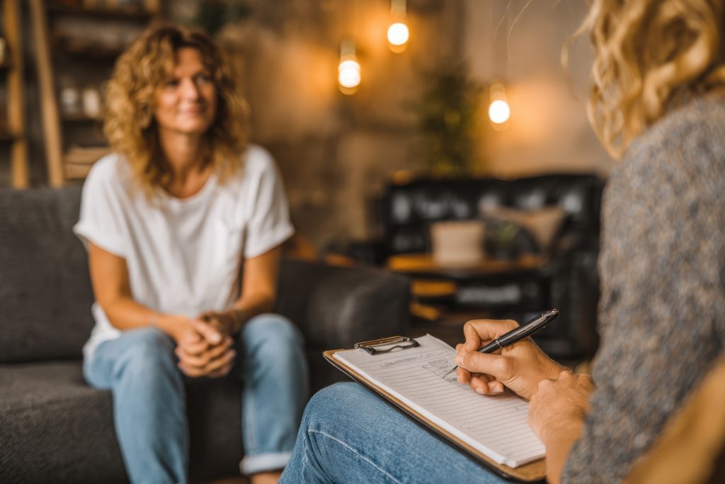 Woman with curly hair sitting on a couch engaged in therapy