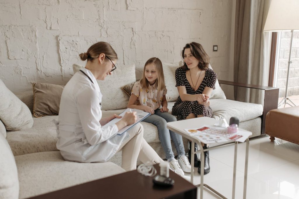 A doctor consults with a mother and daughter in a cozy indoor setting.