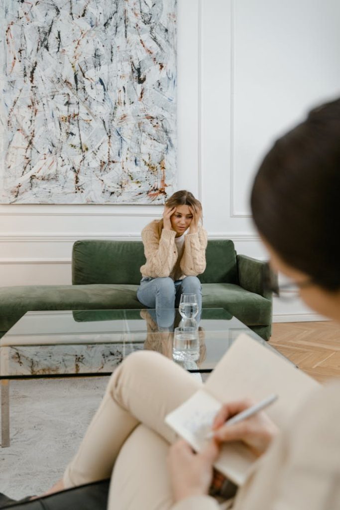 A woman looks distressed during a therapy session indoors, emphasizing mental health support.